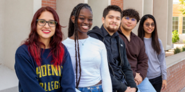 five students leaning against the outside wall of the Fannin Library at Phoenix College