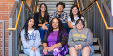 Six students sitting on the steps of the C Building