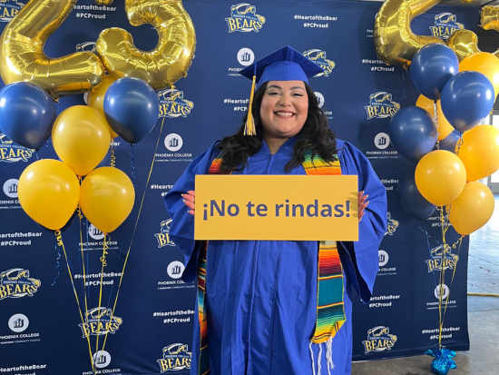 2023 graduating student standing with sign that reads "no te rindas!"