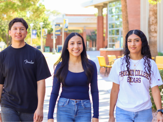 Three students walking on campus near the library